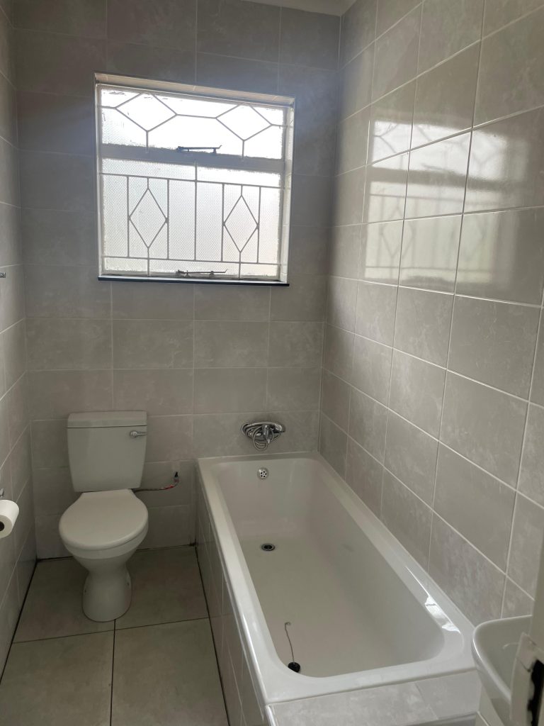 Tiled bathroom with a fitted bath and toilet.